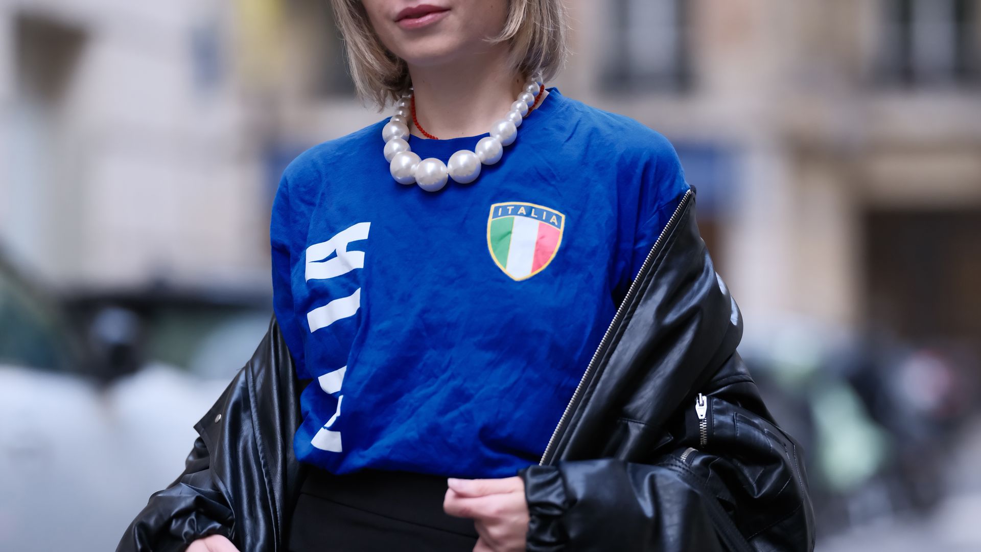 Emy Venturini wears a blue football vintage t-shirt Italia with a printed Italian flag, a black mini skirt from Zara, black bejeweled embellished shoes from Miu Miu, a necklace with large pearls