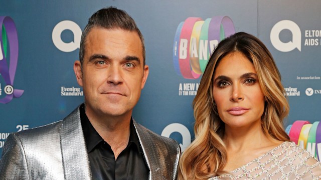 Robbie Williams in a silver tuxedo and Ayda Field in a white dress