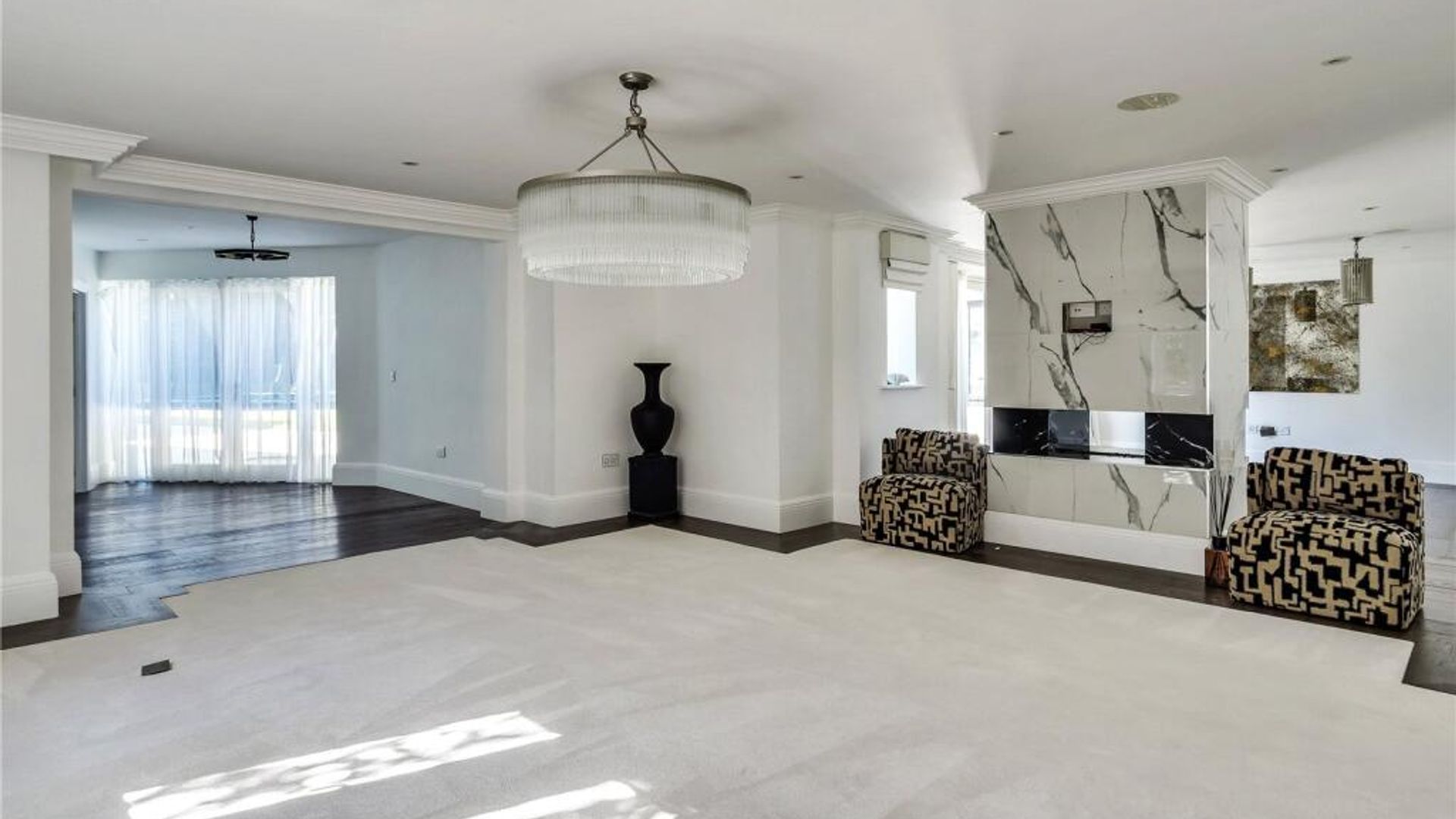 A living room with armchairs, a black vase and a chandelier