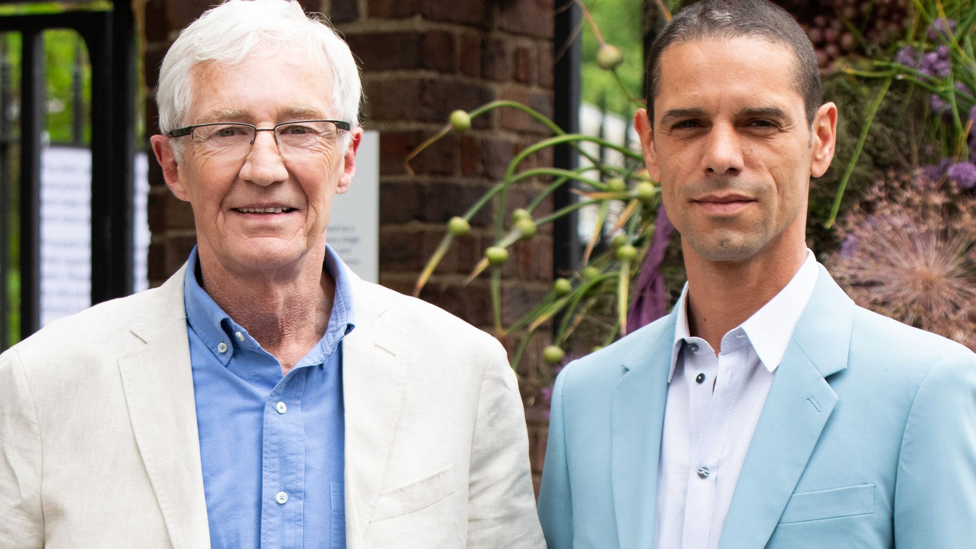 Paul O'Grady wears a cream Etro jacket with Andre Portasio wearing a Sandro blue suit and Dolce & Gabbana shirt