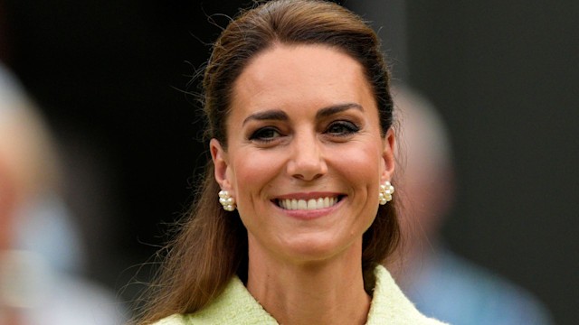 Kate Middleton smiling in a yellow-green dress with her hair in a half updo