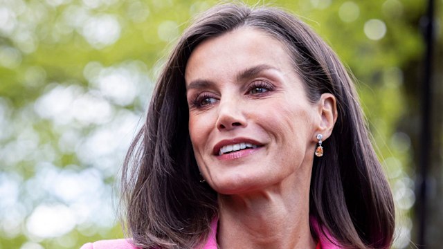 Queen Letizia smiling in red dress and pink coat