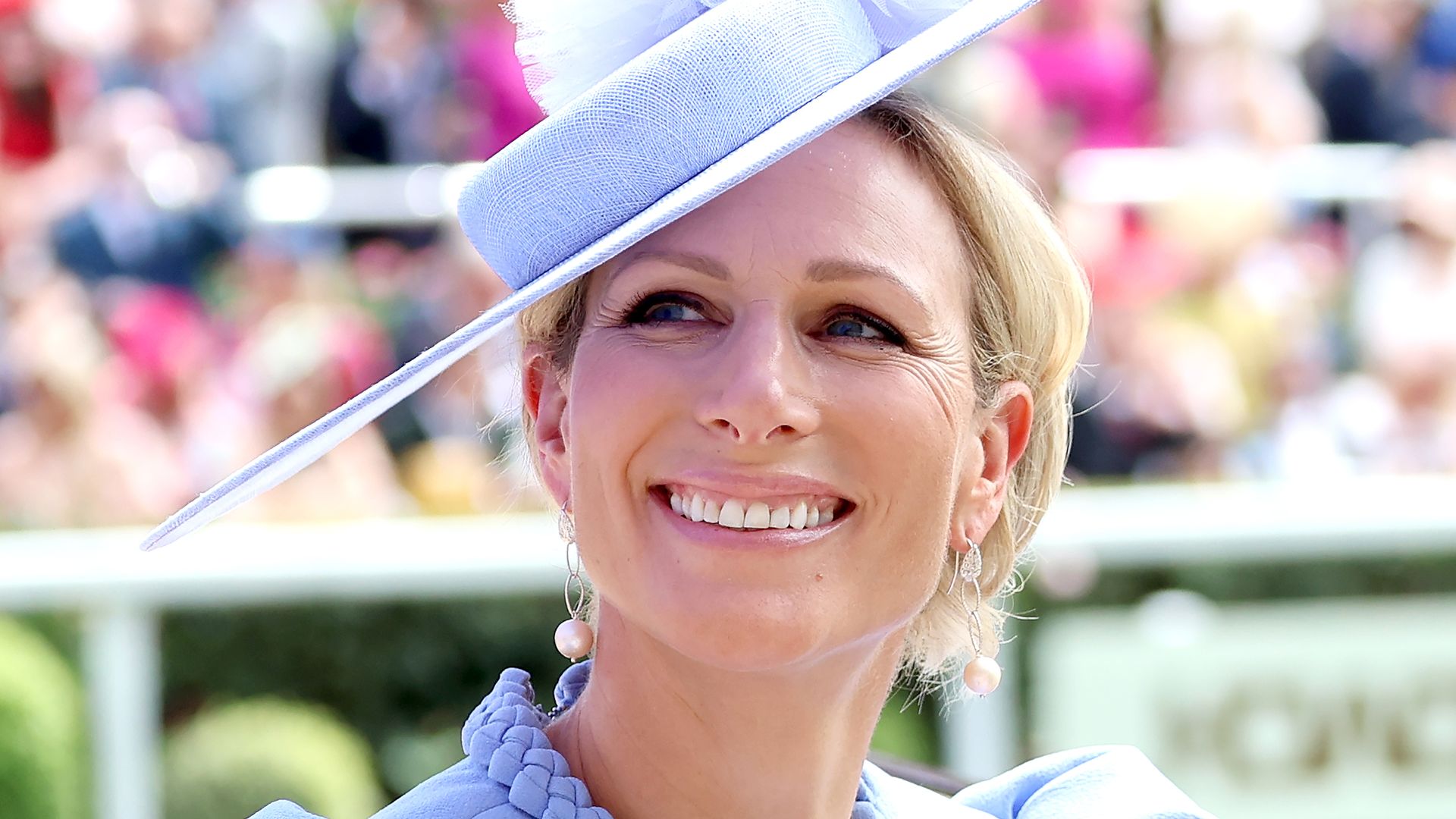 Zara Tindall smiling upwards in blue dress and hat