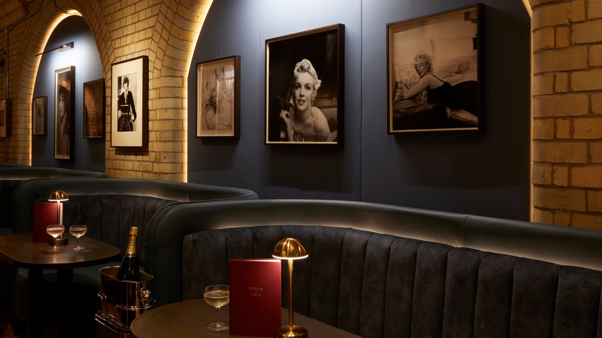 Larry's Bar interior. Velvet blue couches, dimmed gold table lamps and photos of Marilyn Monroe on the wall