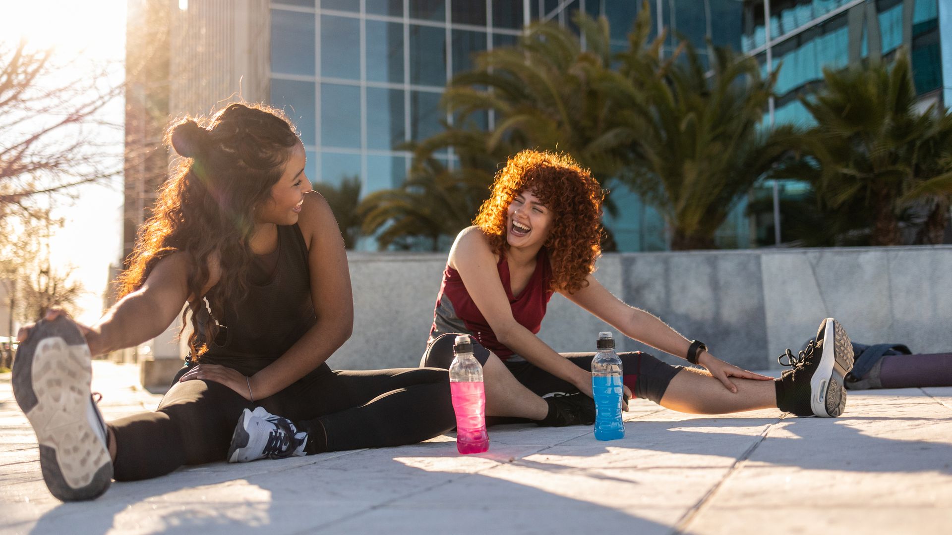 Two young women stretching together outdoors after a workout