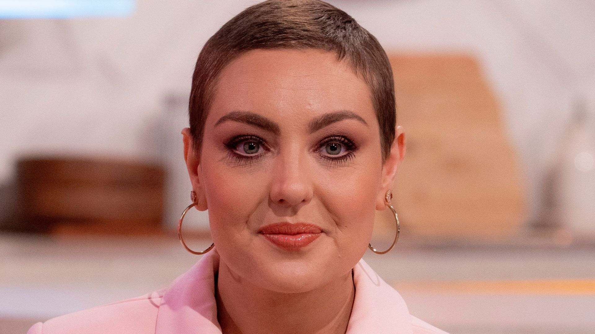 Amy Dowden wearing a pink jacket and hoop earrings