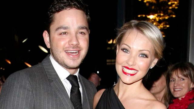 Adam Thomas in a grey suit and Caroline Daly in a one-shoulder dress and red lipstick