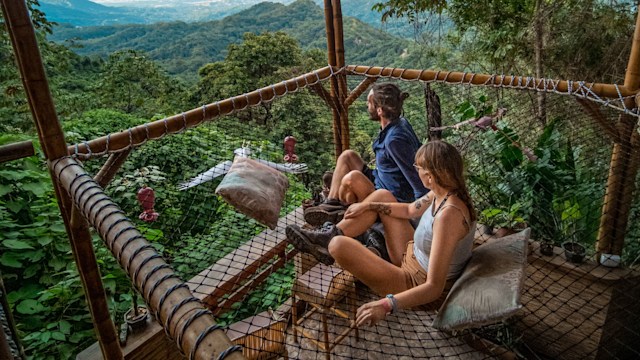 Couple looking out over rainforest from net hammock