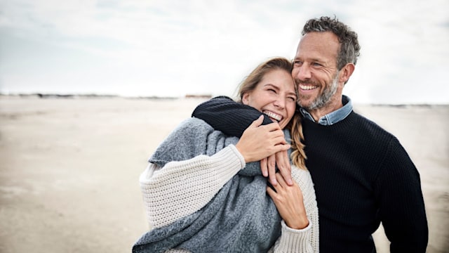 Happy couple hugging on the beach and laughing 