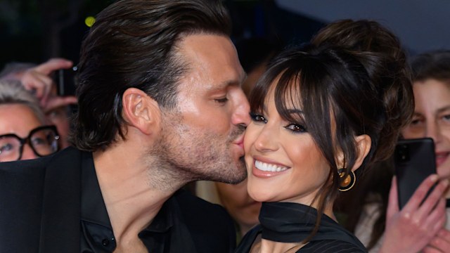 Mark Wright and Michelle Keegan both wearing black as they stand on red carpet at the NTAs, with Mark kissing his wife on the cheek