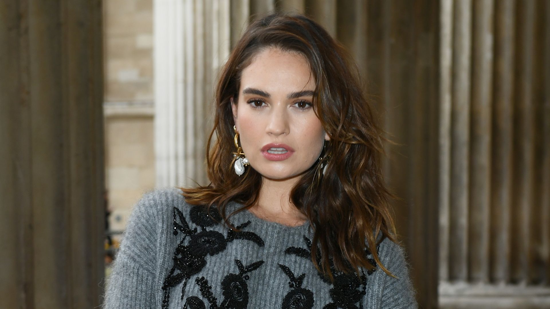 Lily James wearing a fuzzy grey jumper with elaborate embroidery 