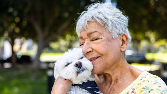 A senior woman holding her puppy outdoors