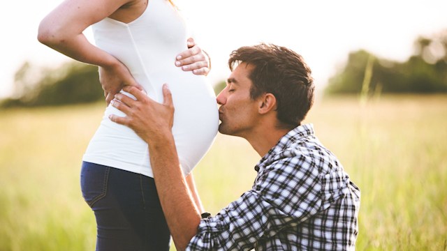Man kissing the belly of his pregnant woman