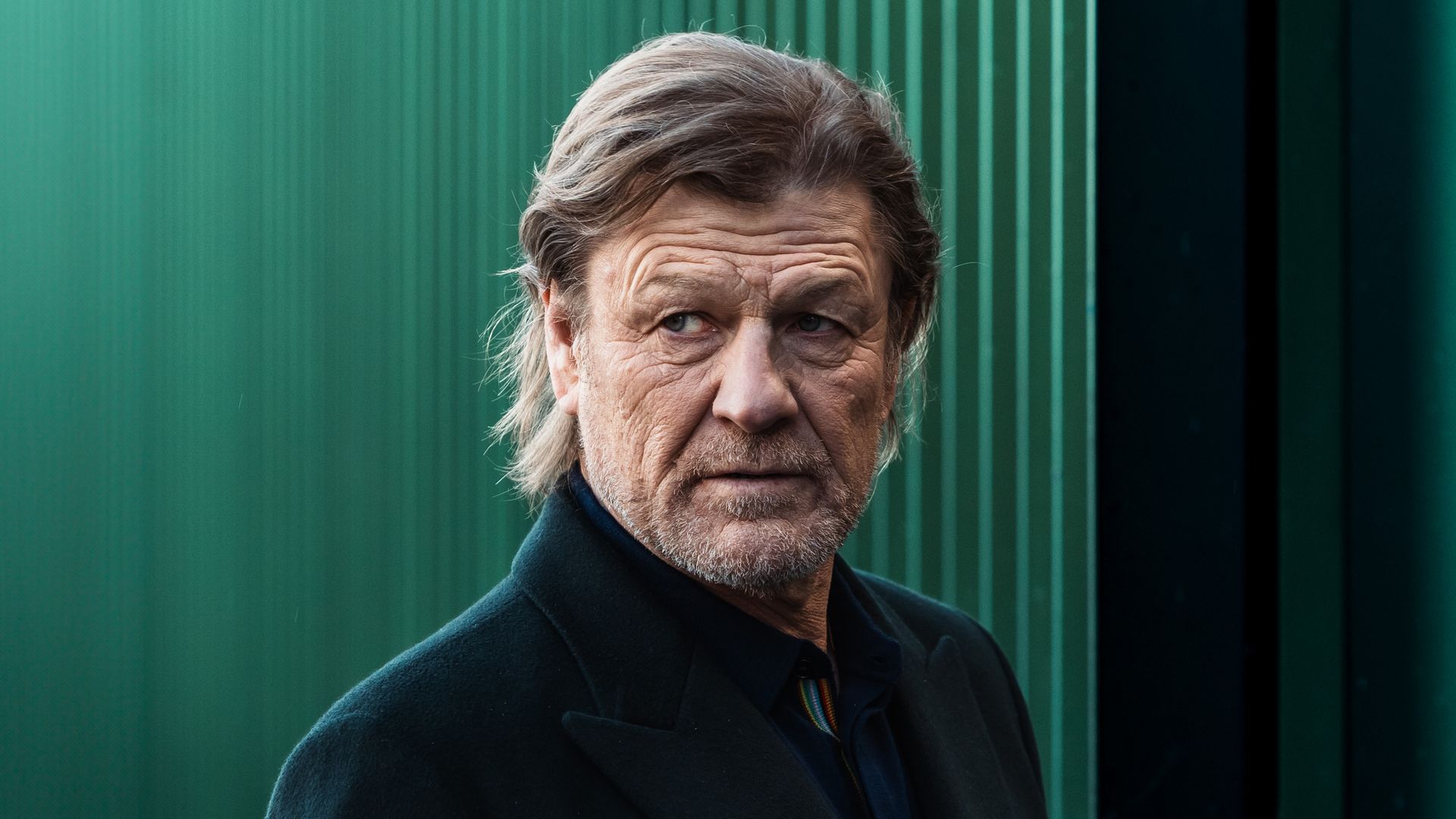 man standing beside green wall