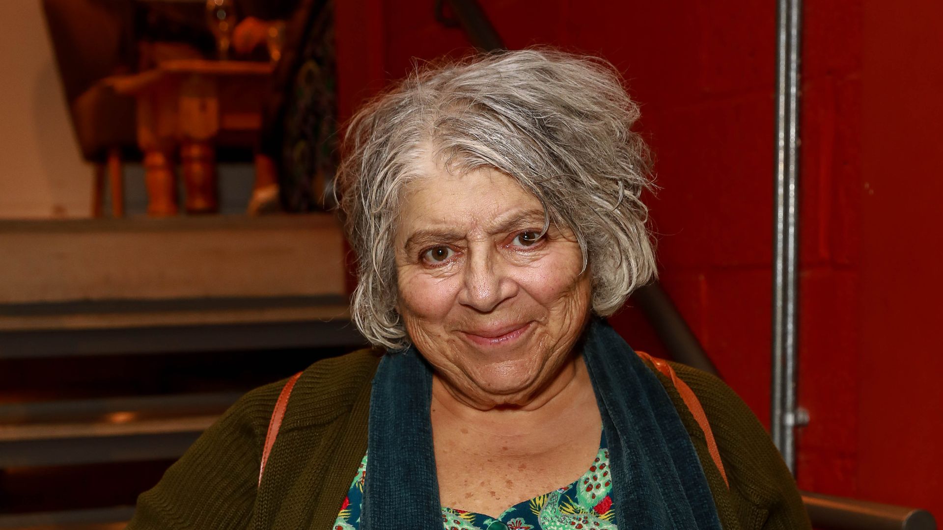 woman with grey hair wearing dress cardigan and scarf