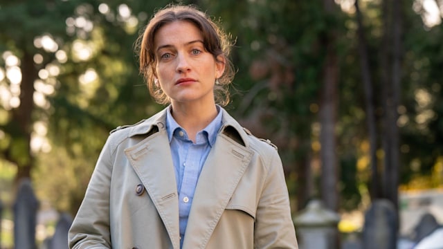 Woman with brunette hair looking into the camera in graveyard