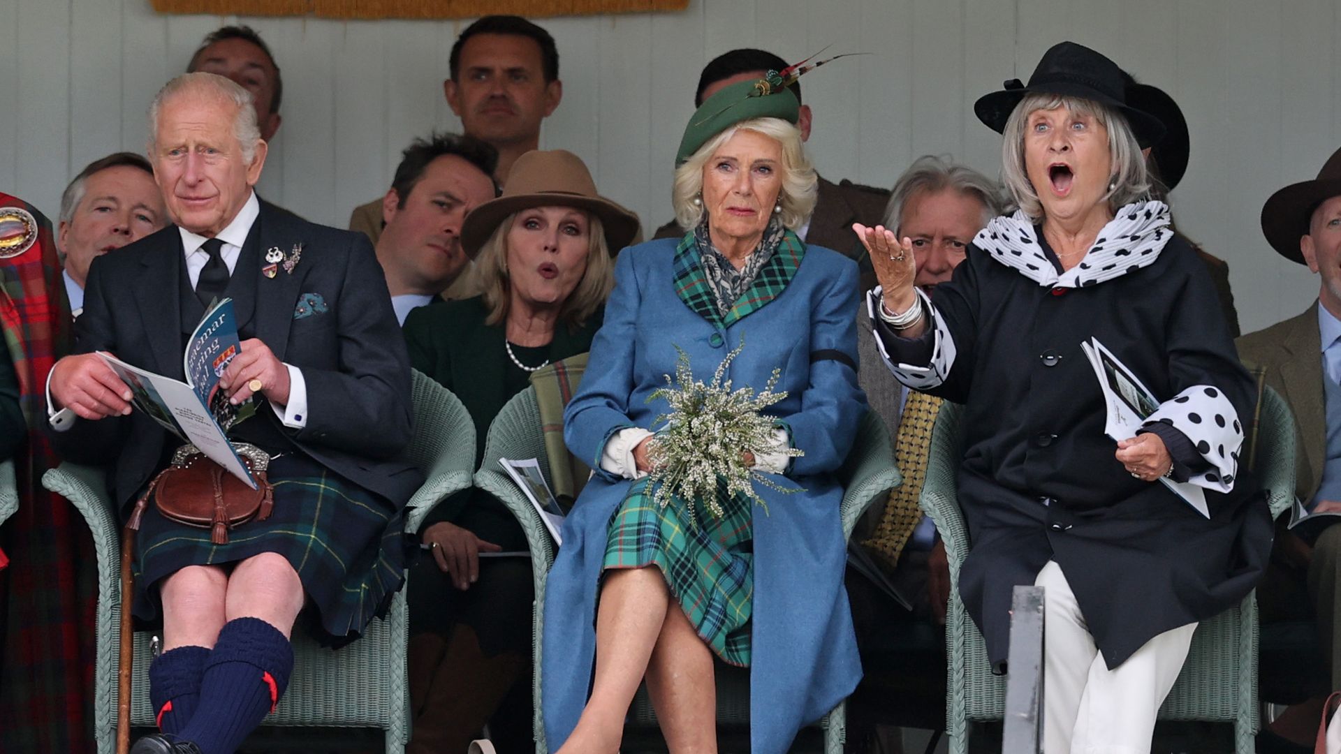 King Charles sitting with Queen Camilla and Baroness Helena Kennedy, Joanna Lumley is in the background