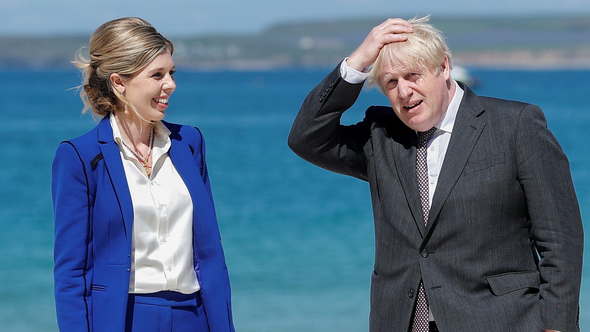 Boris Johnson and his spouse Carrie Johnson by beach in suits