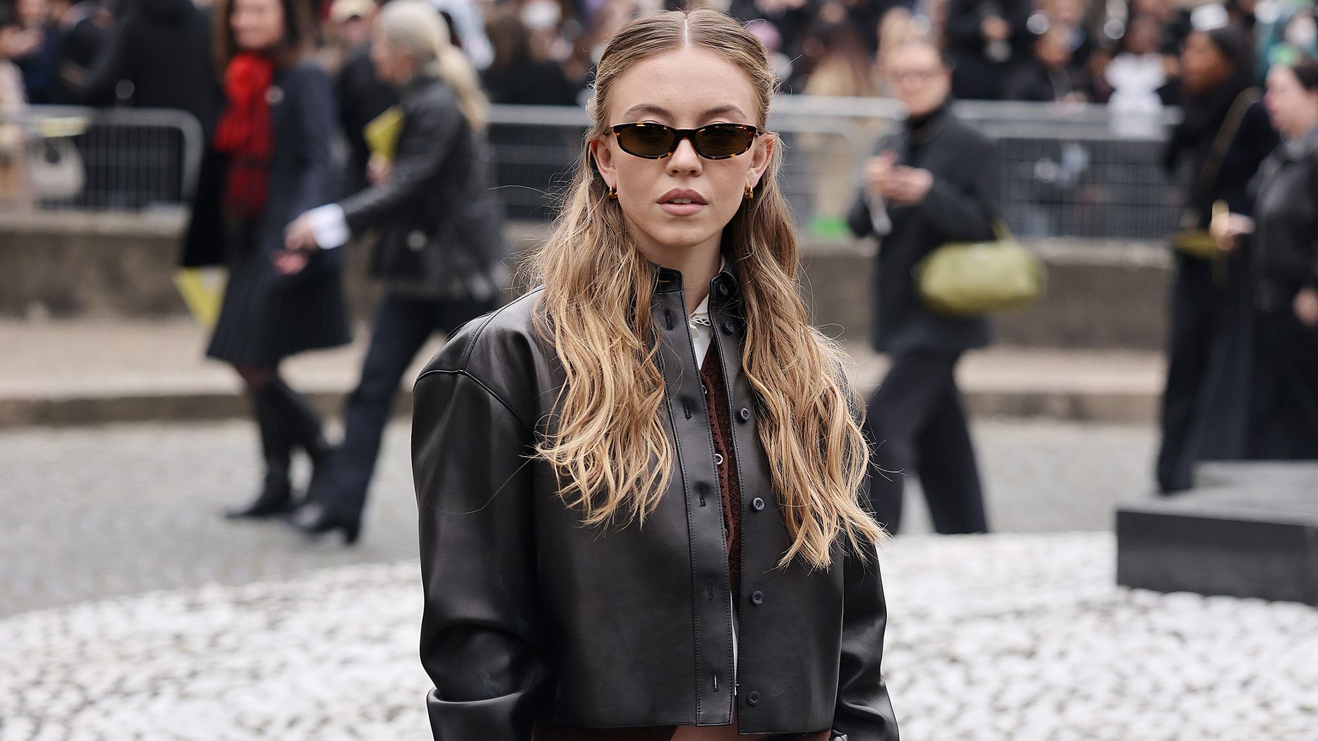 Sydney Sweeney attends the Miu Miu show in brown leather skirt and jacket