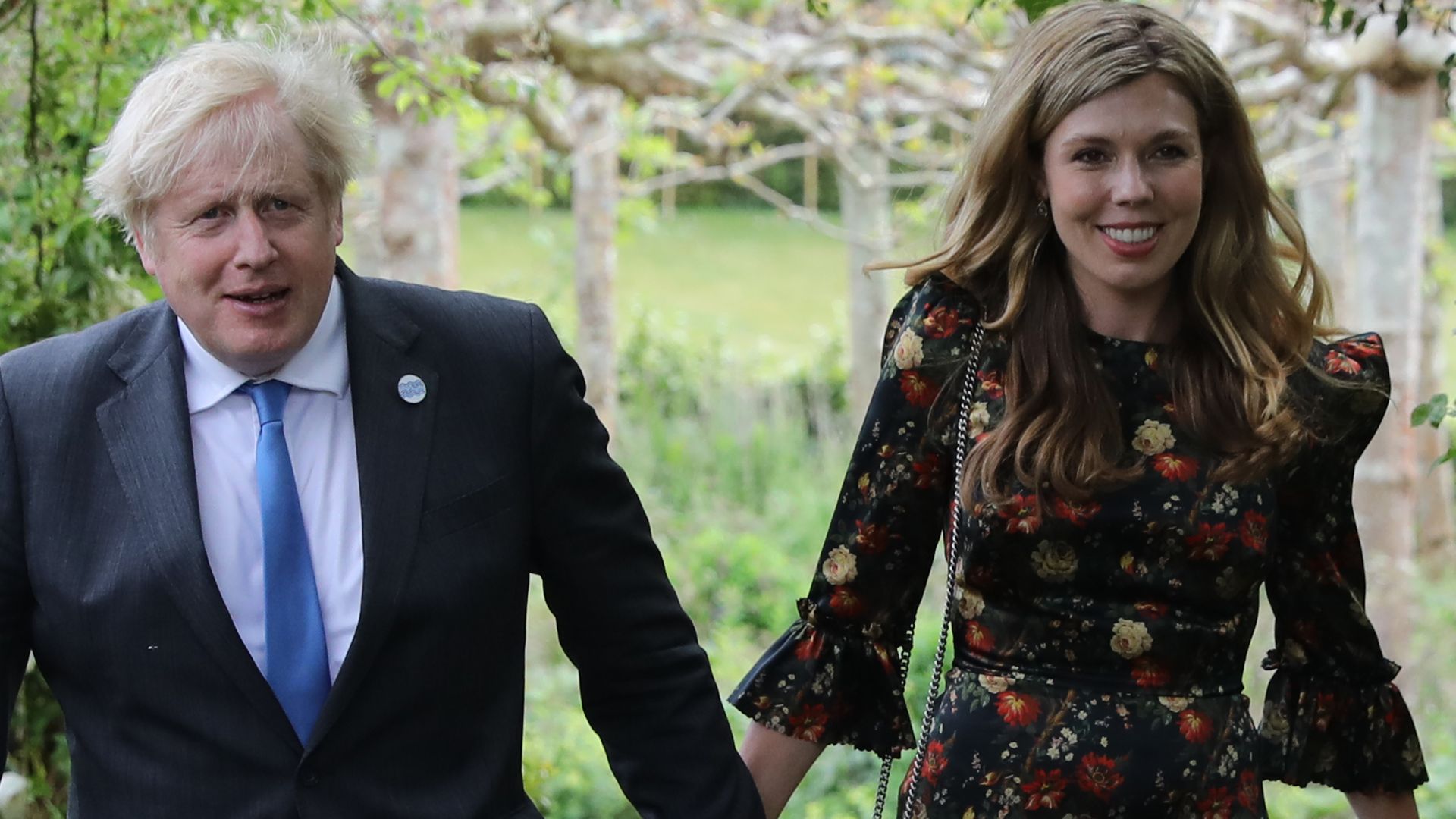  Boris Johnson and his wife Carrie Johnson walking through a floral arch in a garden