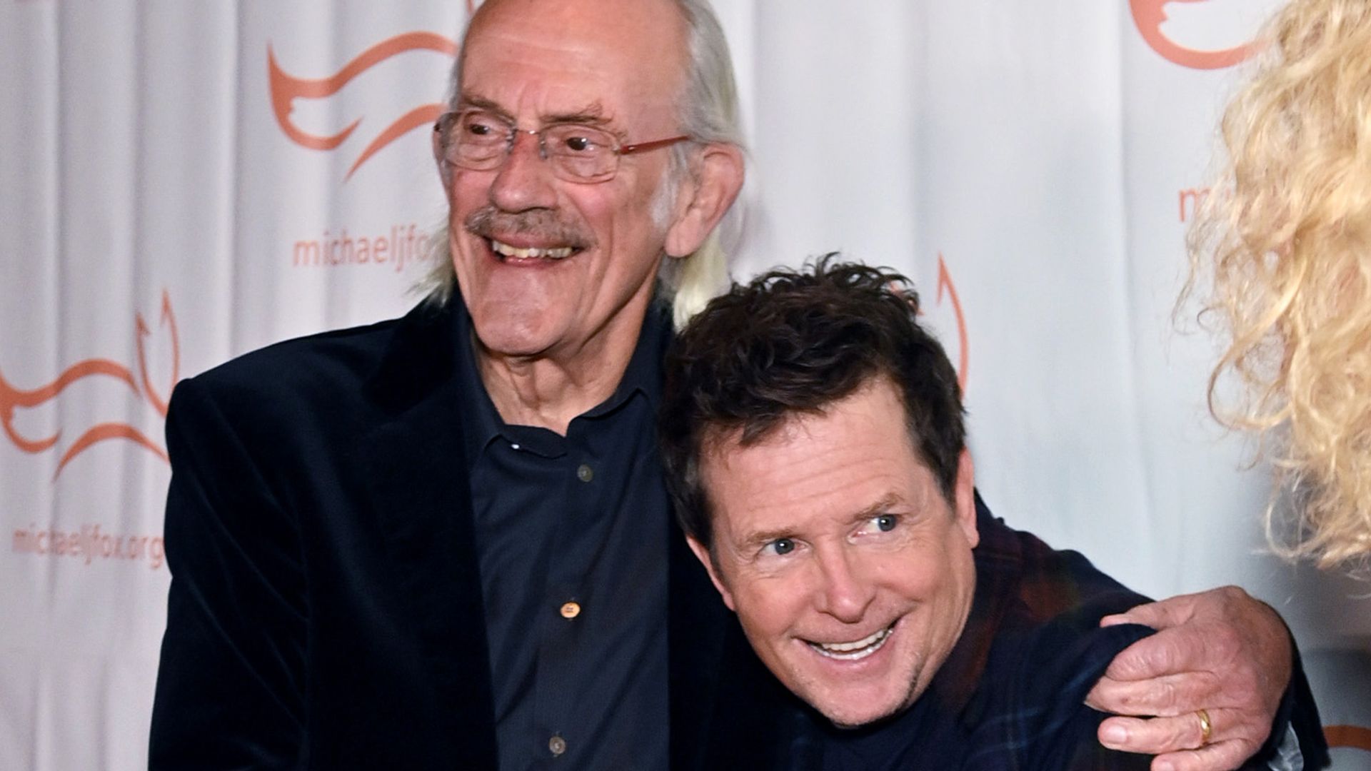 Christopher Lloyd and Michael J. Fox hug as they attend the 2023 A Funny Thing Happened On The Way To Cure Parkinson's event at Casa Cipriani