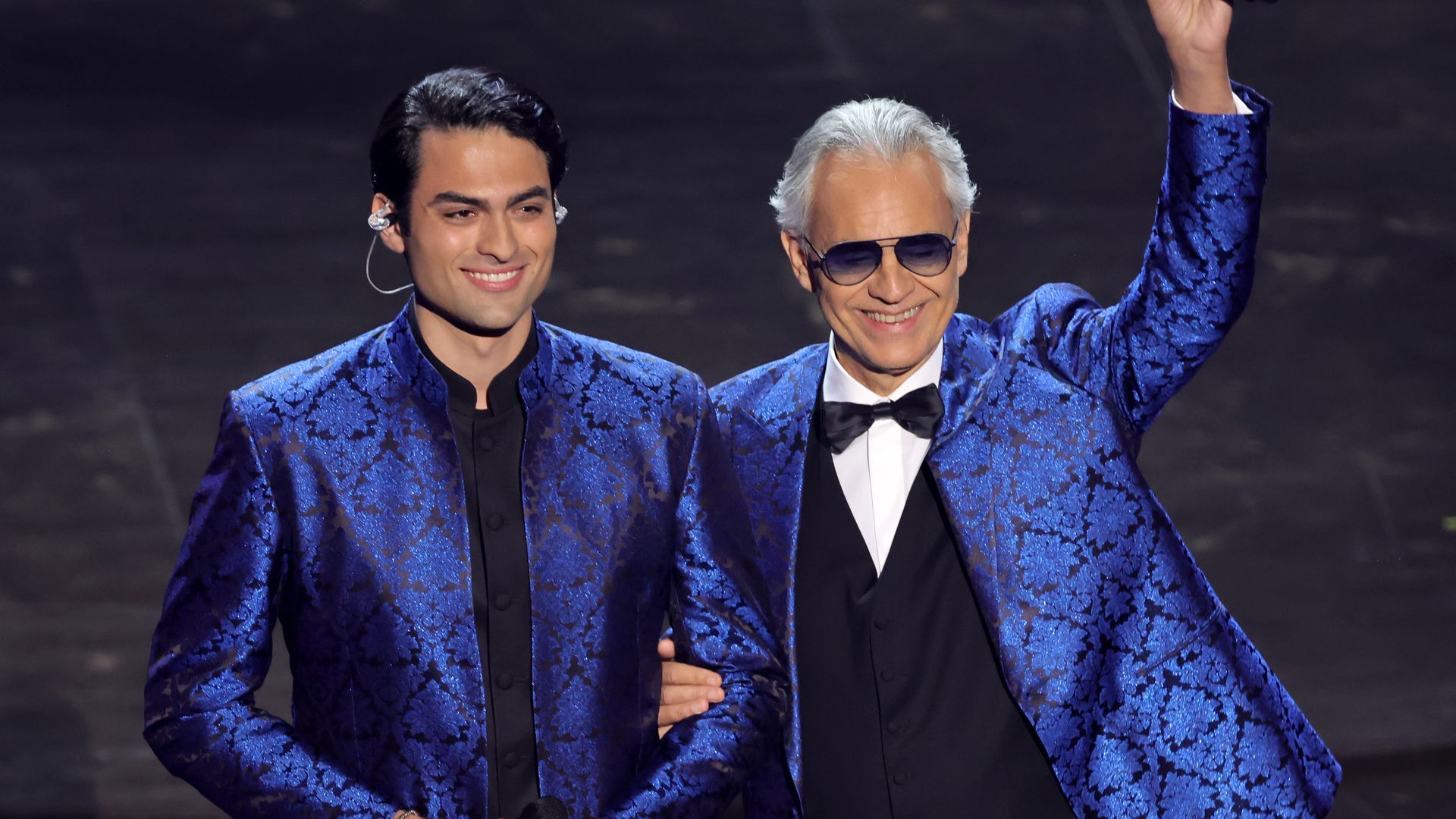Matteo Bocelli and Andrea Bocelli onstage in matching cobalt blazers