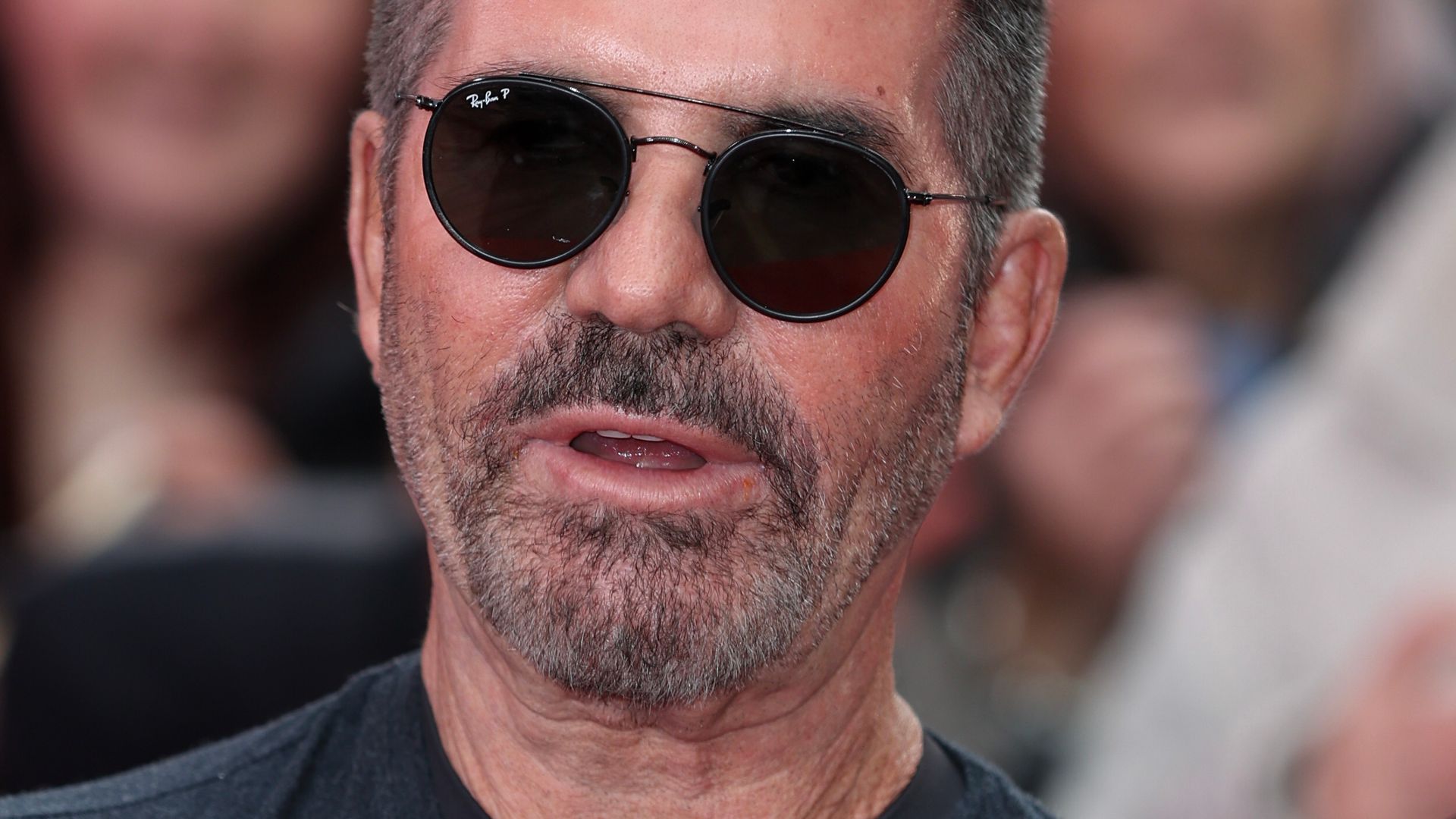 Simon Cowell wearing sunglasses and a dark grey tshirt