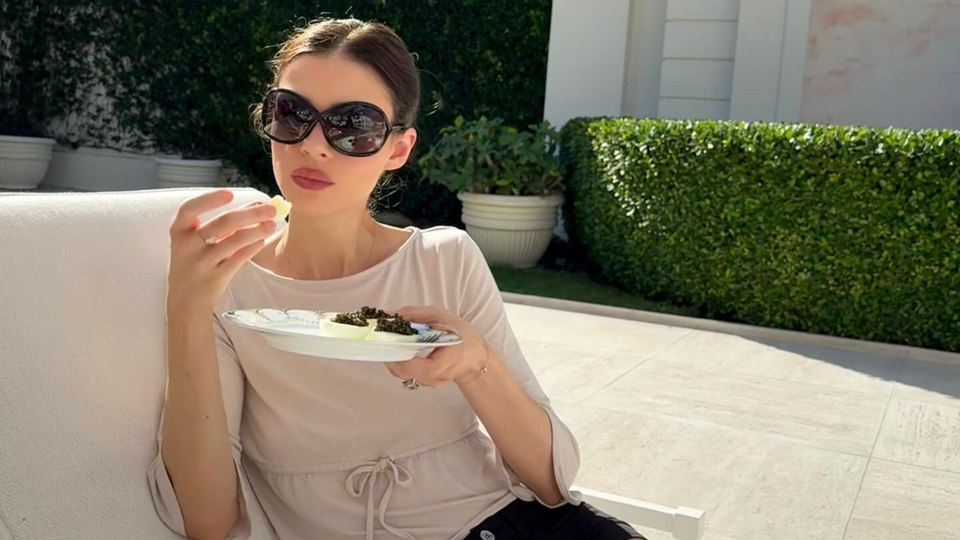 Nicola Peltz sitting in the sun in shorts