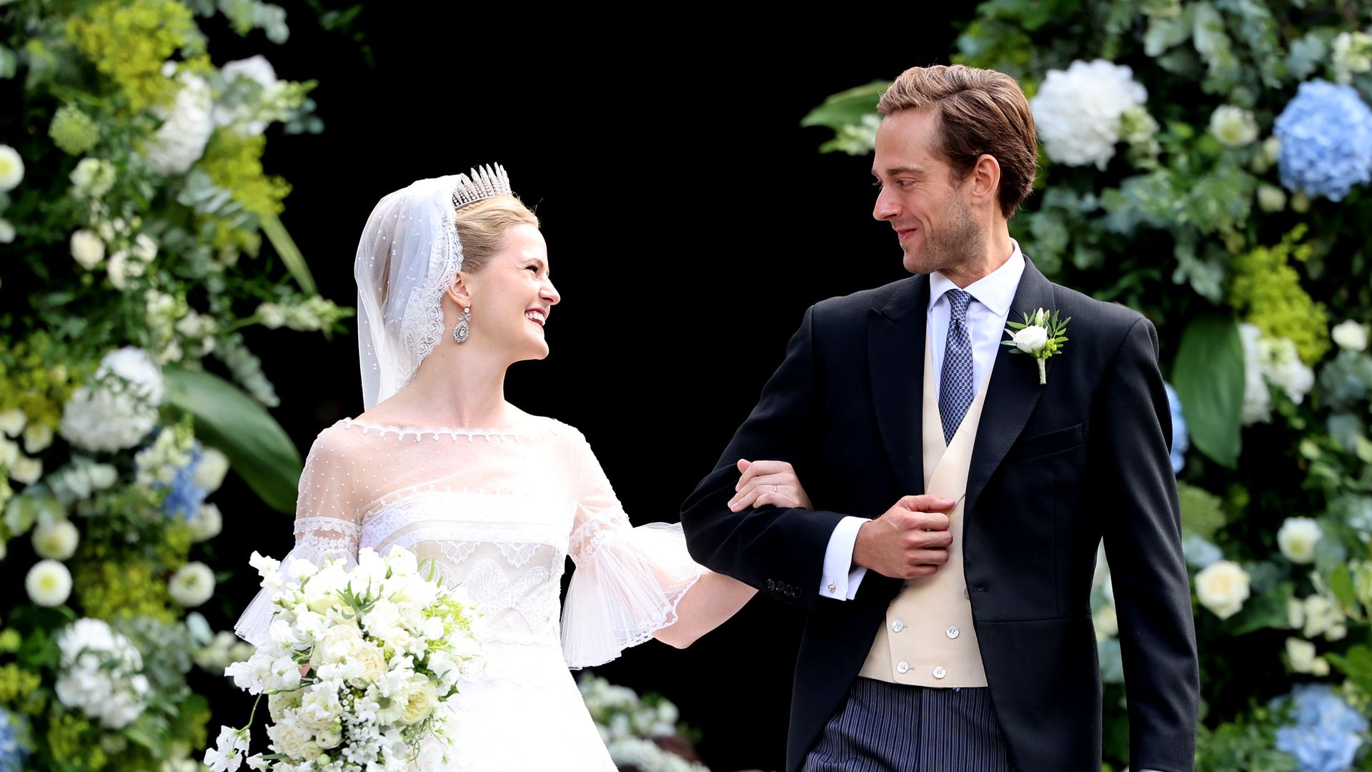 Princess Marie Caroline of Liechtenstein in bridal gown looking at husband smiling
