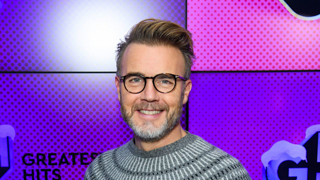 man posing in grey jumper and glasses