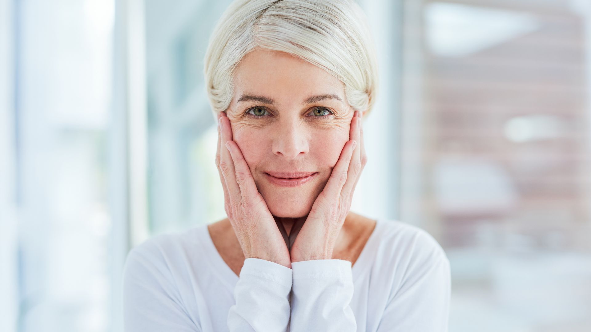 Anti-ageing skin teratments - Portrait of a mature woman touching her face in a bathroom at home
