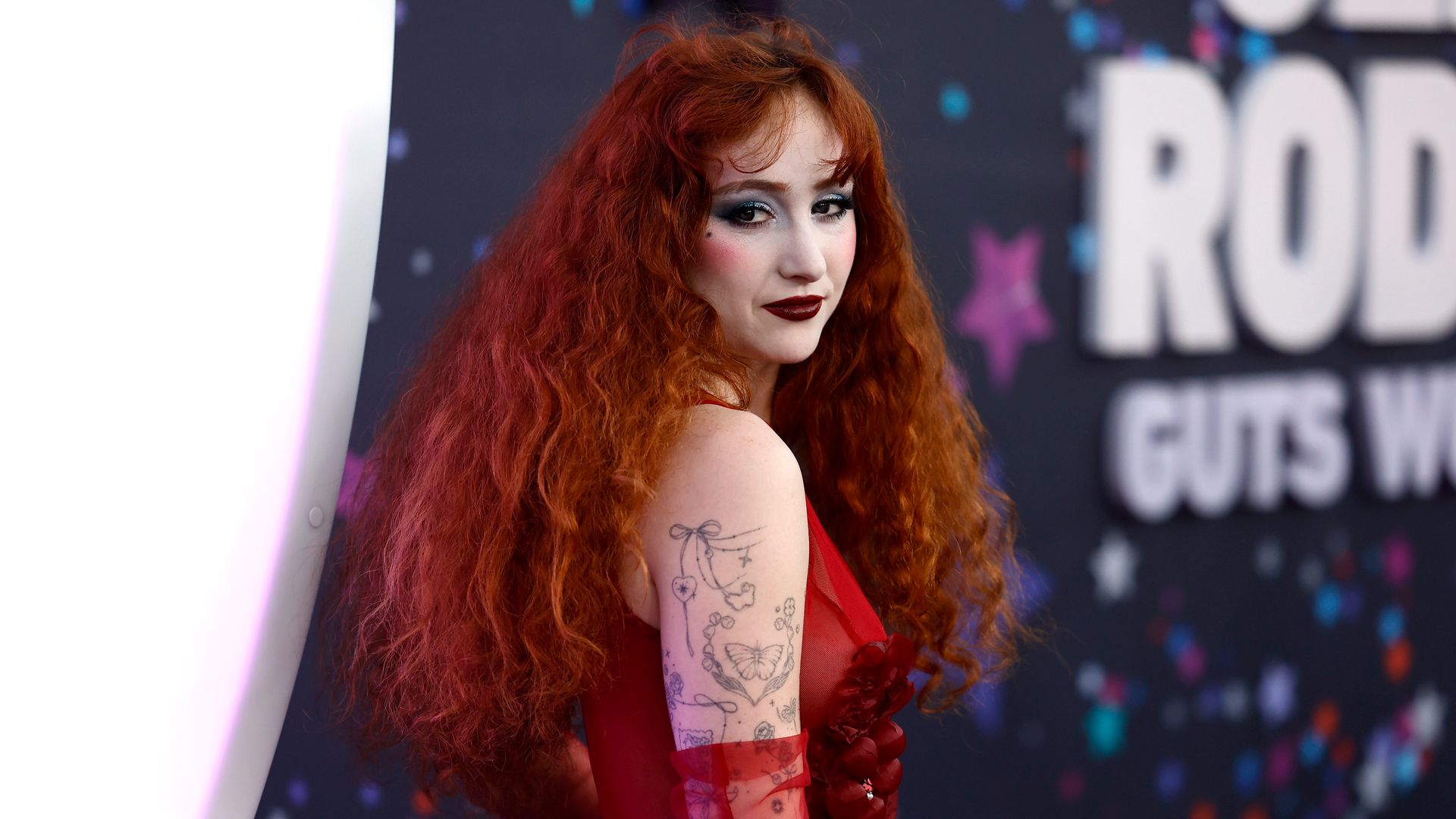 Chappell Roan in red dress and gloves while on red carpet for the premiere of Netflix's Olivia Rodrigo: GUTS World Tour 