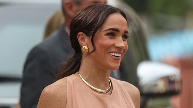 Prince Harry in cream shirt and Meghan in blush dress smiling