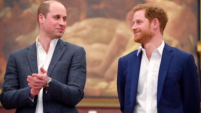 Prince William and Prince Harry smiling at eachother in suit jackets and shirts
