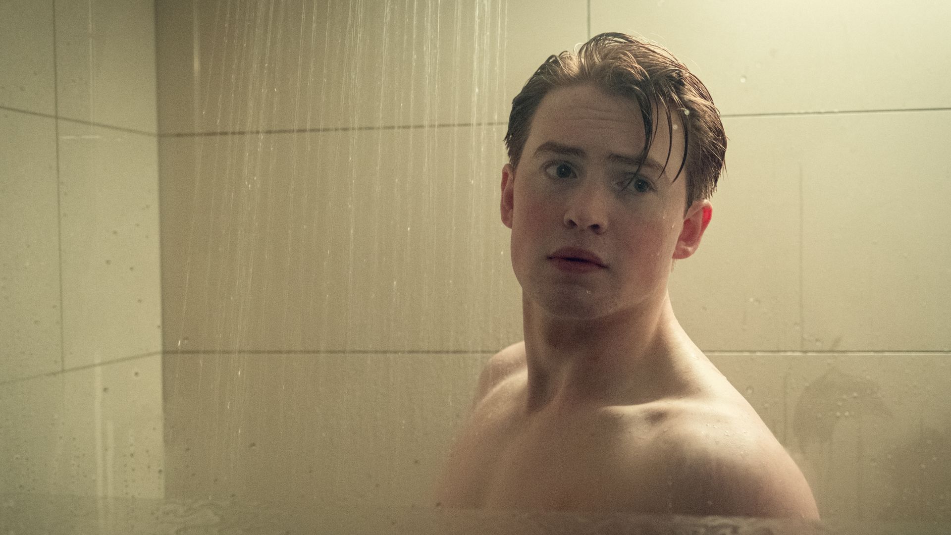 Kit Connor, as Nic, stands in the shower in a scene from Heartstopper