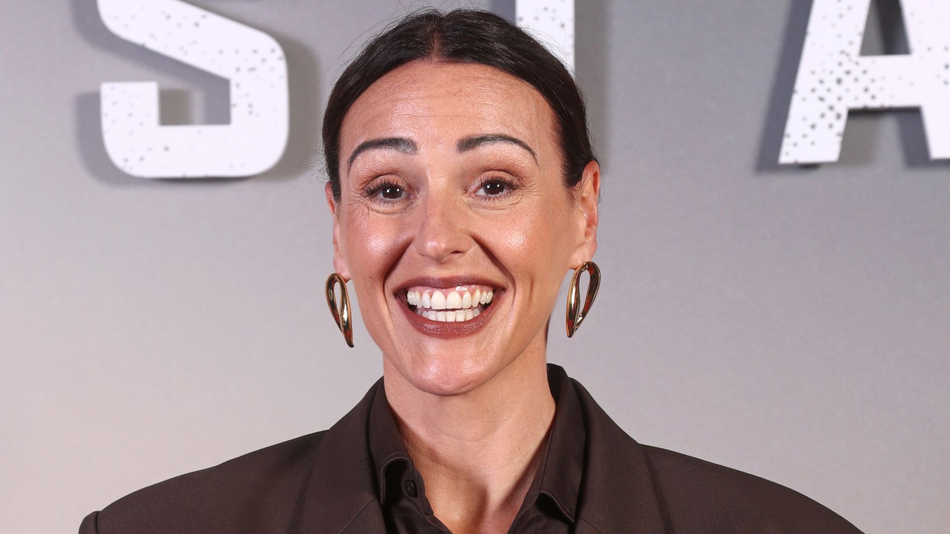 Suranne Jones beaming in a brown suit