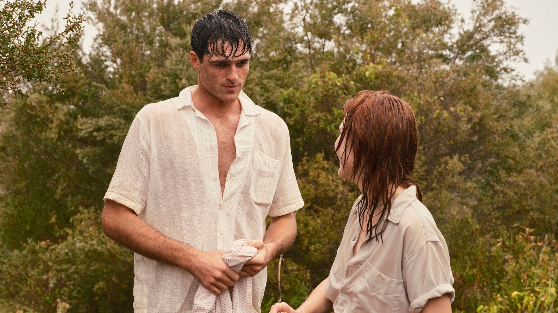 man and woman talking in front of bushes