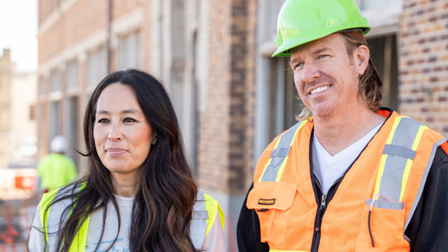  Joanna Gaines and Chip Gaines wear hard hats and high vis vests outside a property