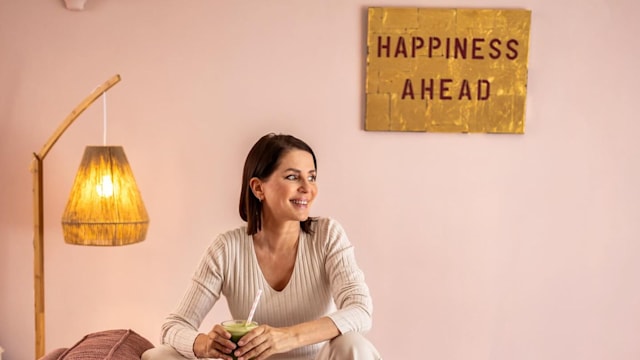 Sadie Frost smiling on a pink sofa