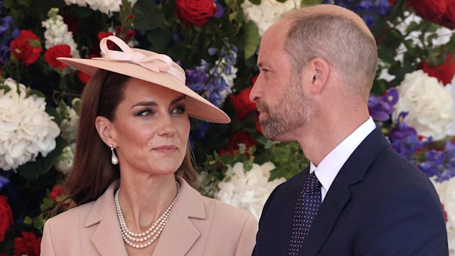 Kate smiling at William in front of floral wall