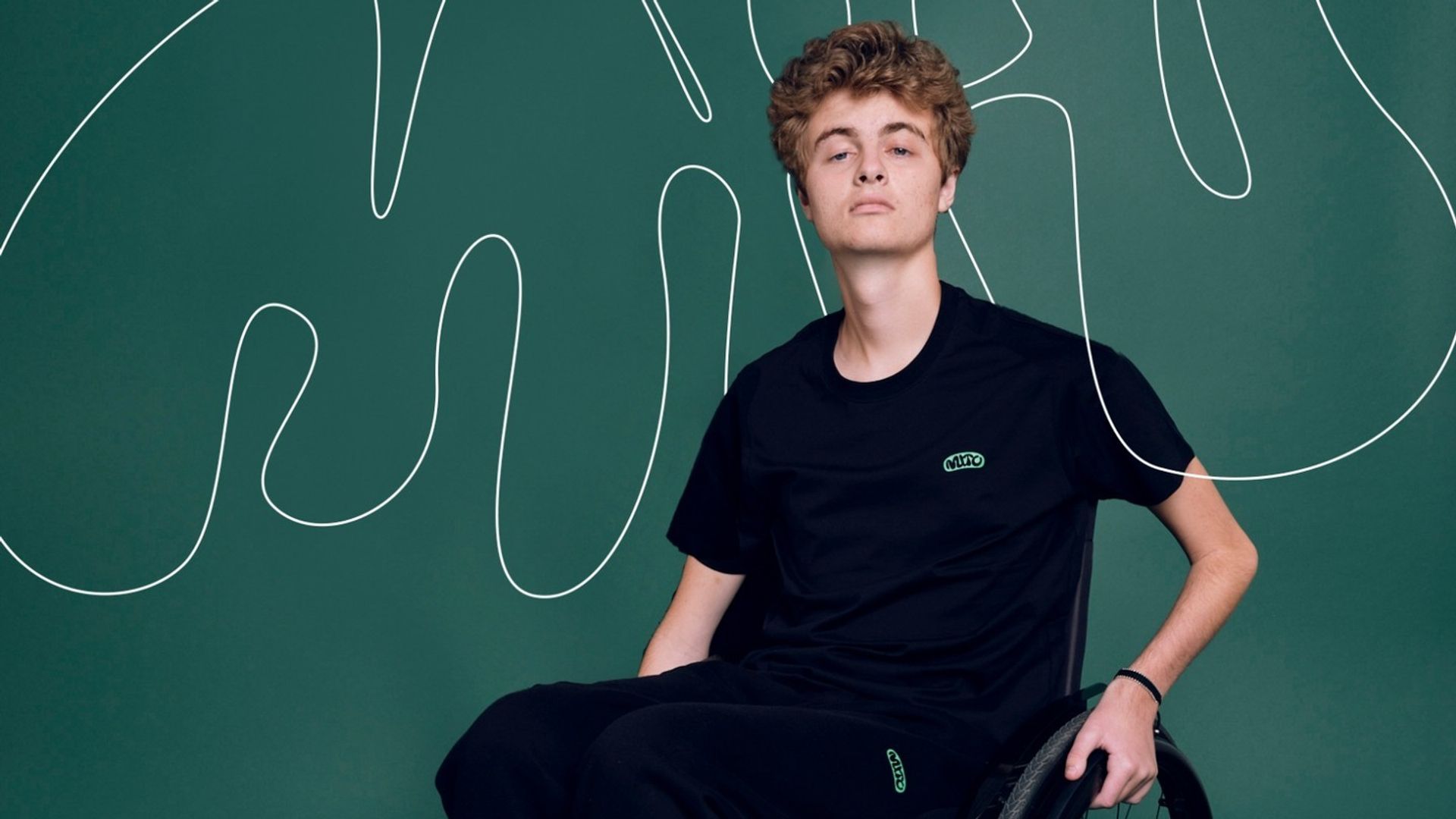 Prince Frederik dressed in black in a wheelchair on a teal green background 