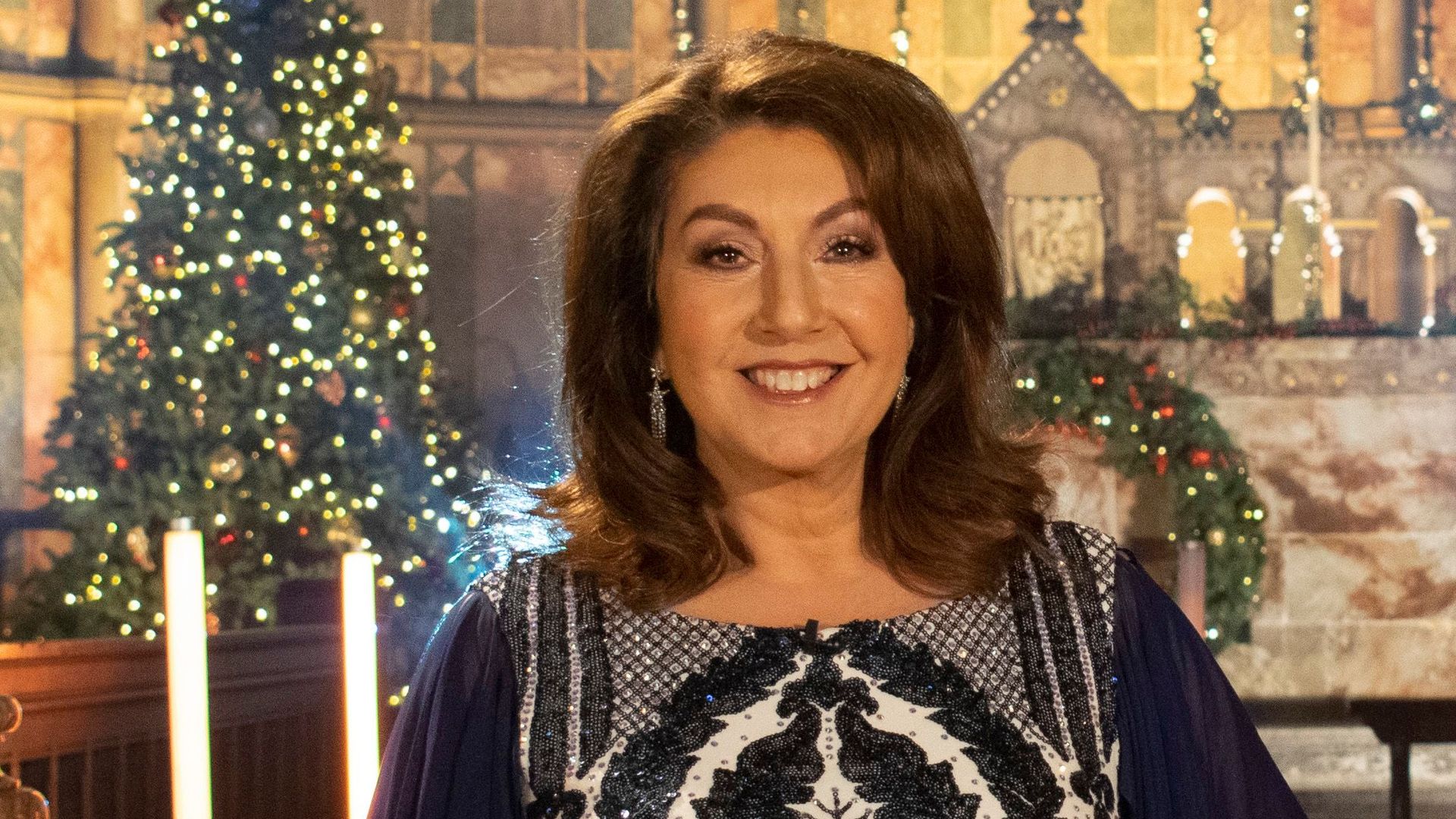 Jane McDonald in sequin dress in front of Christmas trees