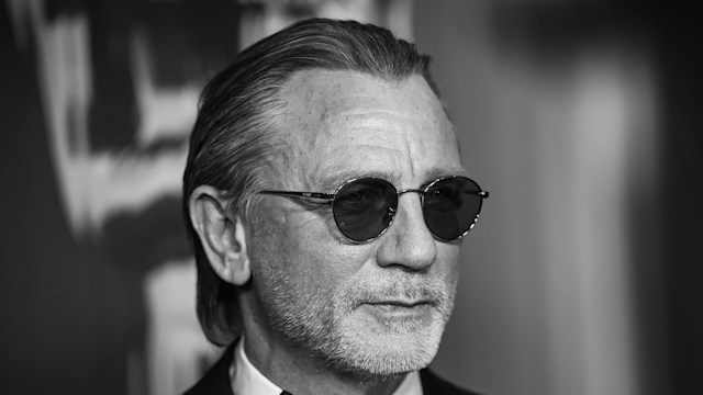 black and white image of man posing in suit and glasses