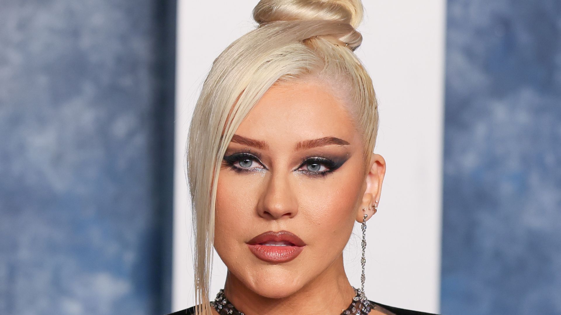 Christina Aguilera in black dress with hair tied up into a bun