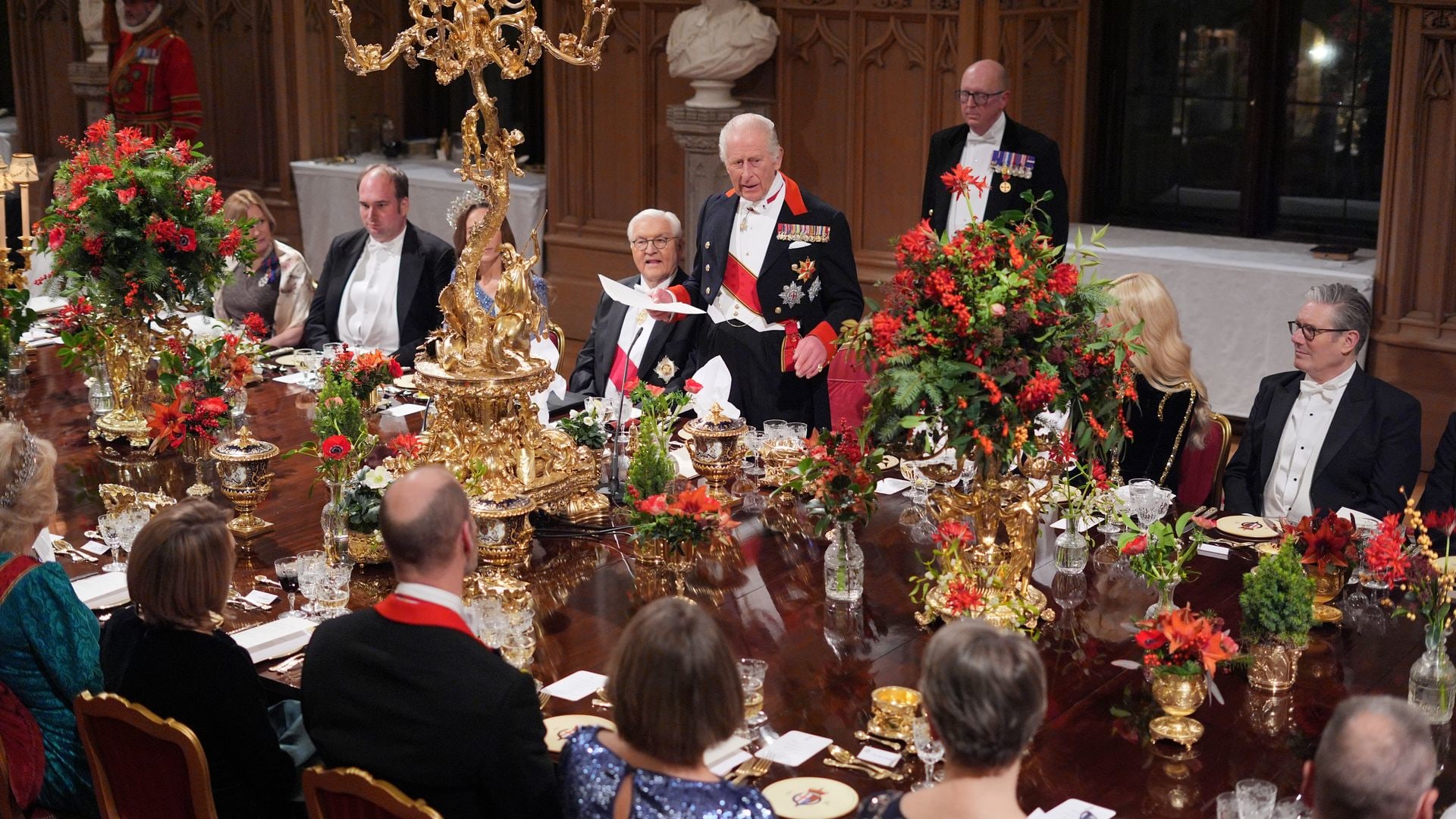 King Charles giving a speech at a crowded dinner table