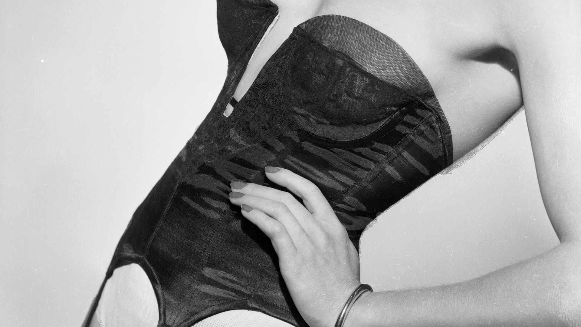 A woman with her hand on her hip wearing a strapless corset with suspenders attached