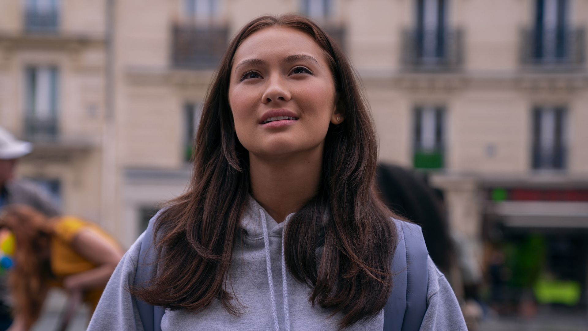 young woman in grey jumper standing in city street