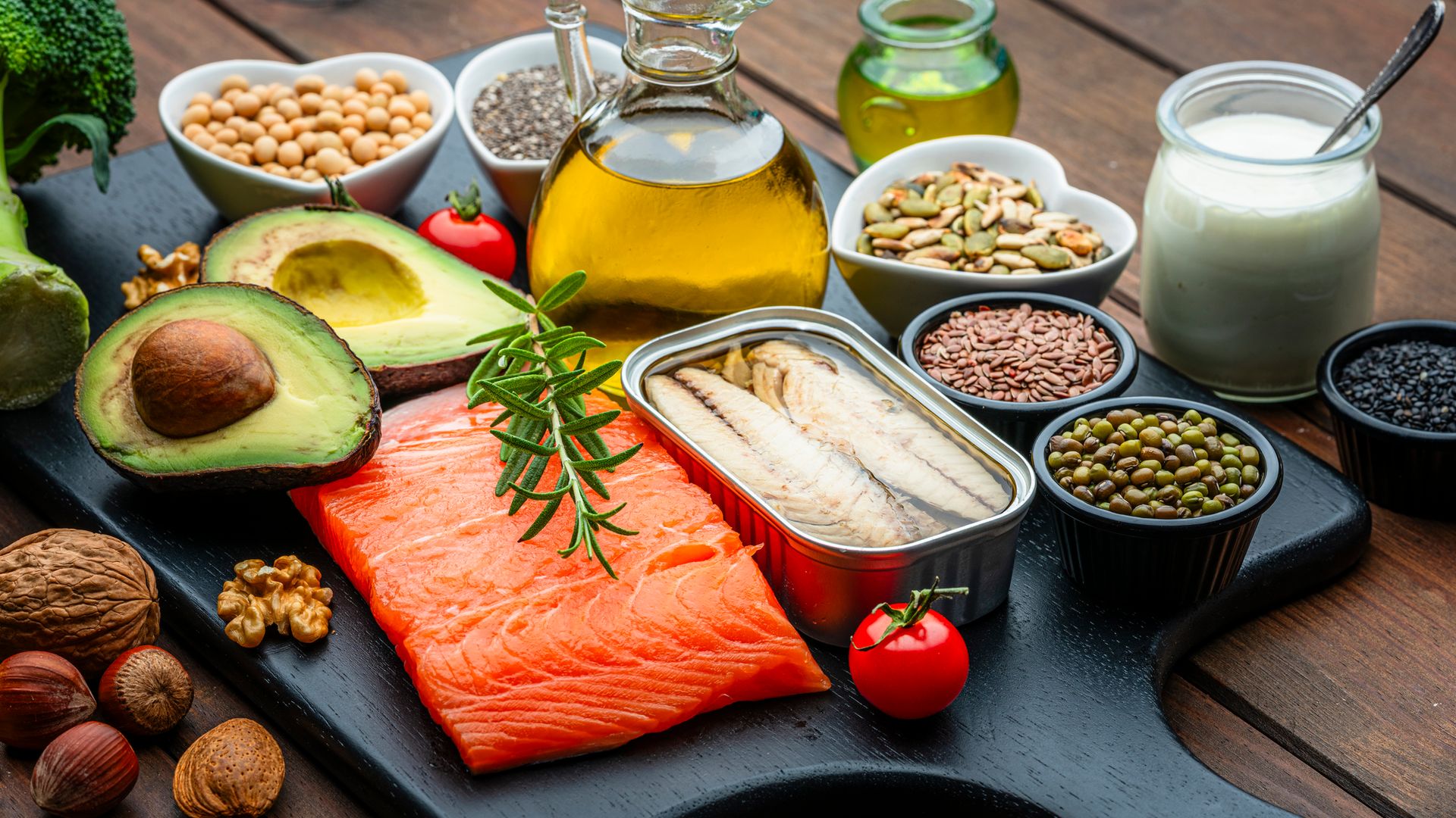 Group of healthy ingredients including olive oil, avocado, salmon, sardine, chia seed, nuts