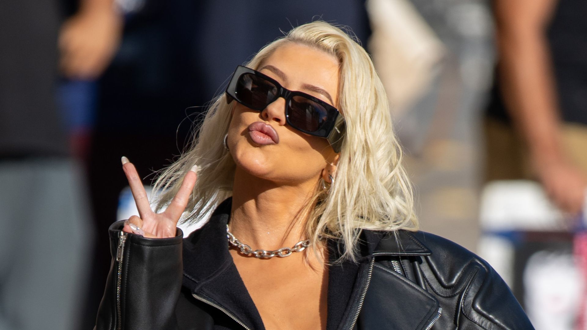 Christina Aguilera making a peace sign in black leather outfit