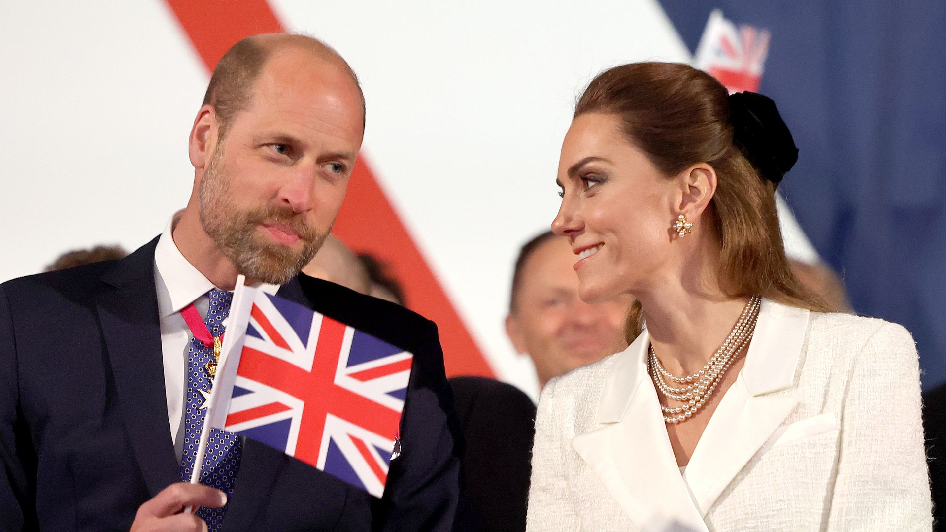 William and Kate smiling at each other and waving flags